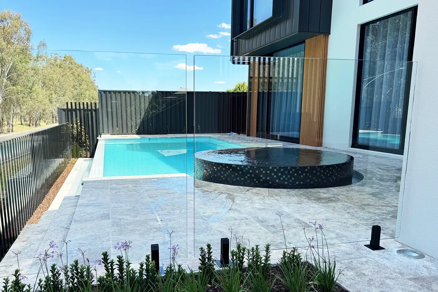 Infinity edge pool with round elevated infinity spa finished in black pearl tiles Concrete Swimming Pools Shepparton, infinity edge pool, with round elevated infinity spa, finished in black pearl tiles